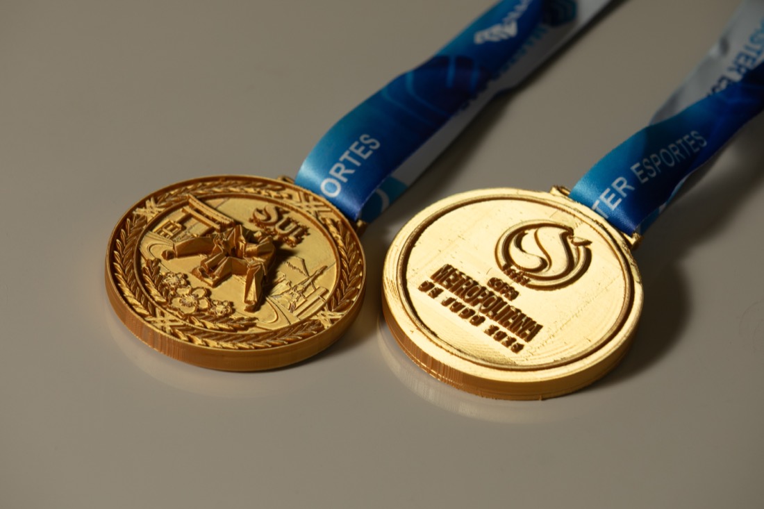 Duas medalhas de eventos diferentes lado a lado, cada uma com arte própria.