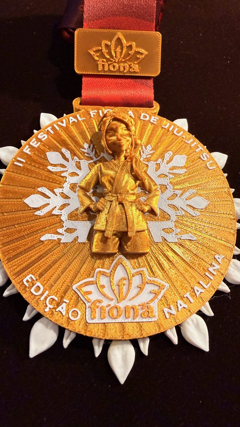 Medalha do Festival Fiona de Jiu-Jitsu, dourada com flocos de neve brancos e a personagem do evento em relevo.