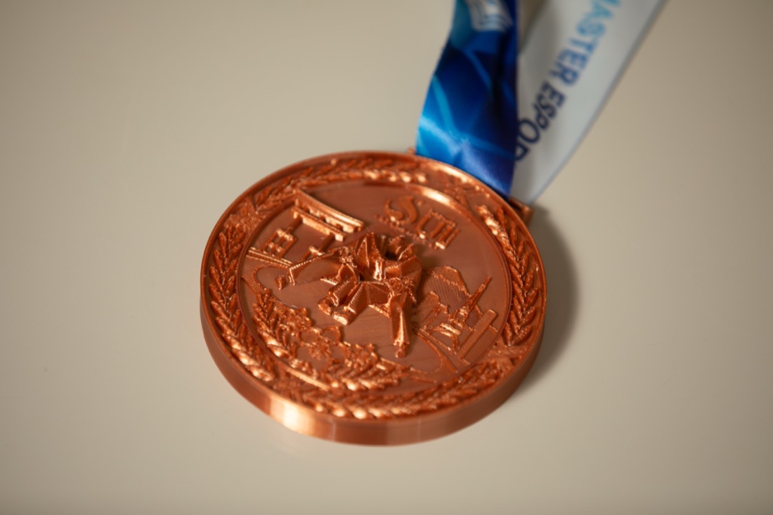 Medalha 3D em acabamento cobre com fita azul.