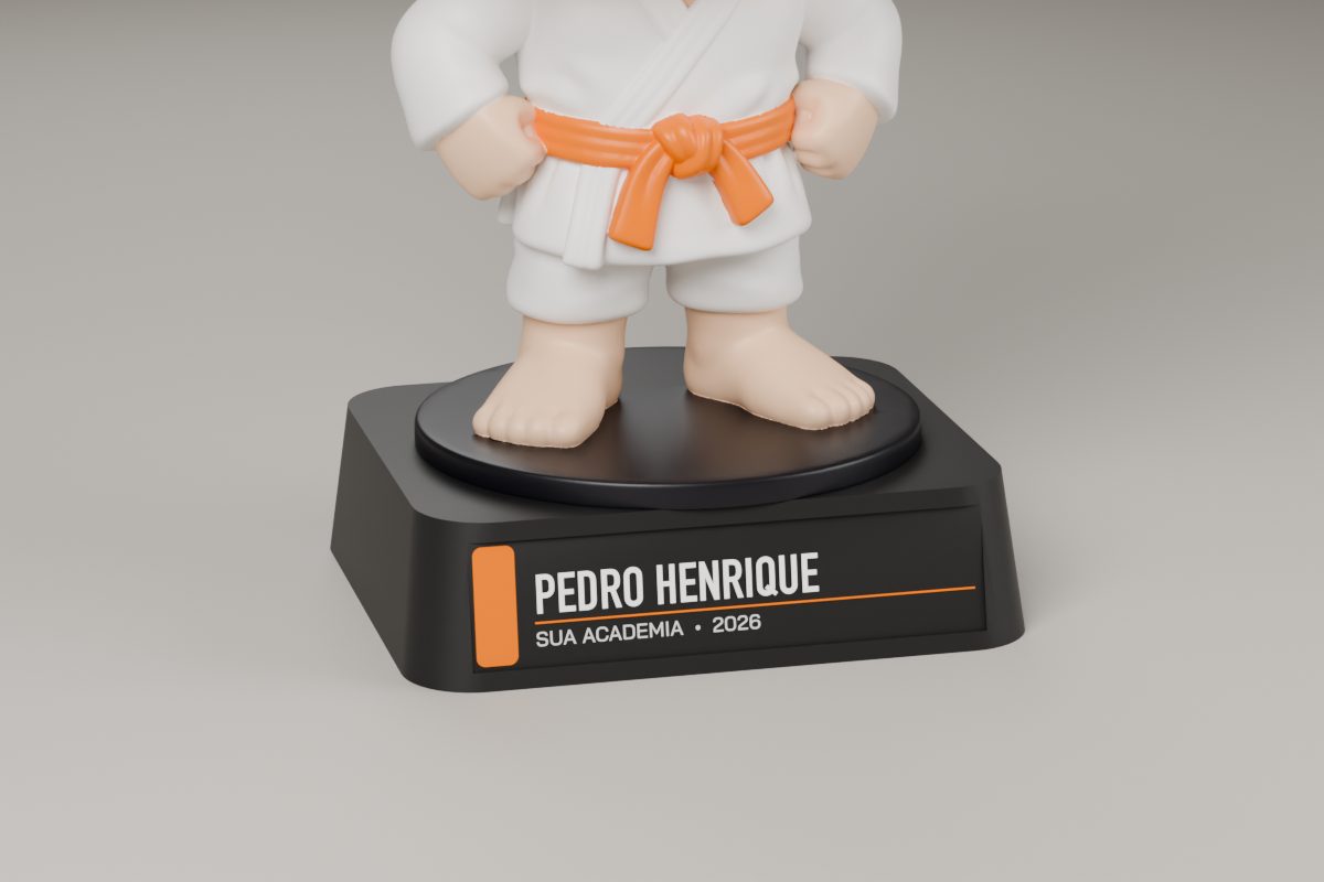 Base preta do cabeçudinho de faixa laranja com o adesivo Pedro Henrique, Sua Academia, 2026, e a tarja laranja.
